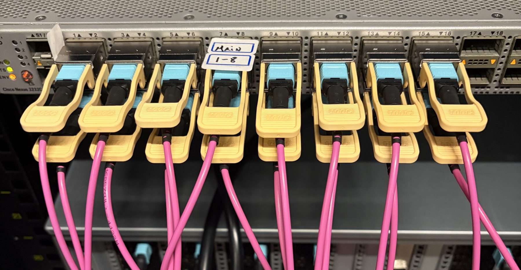 Close view of a network switch port row with optical transceivers and fibre latched in.